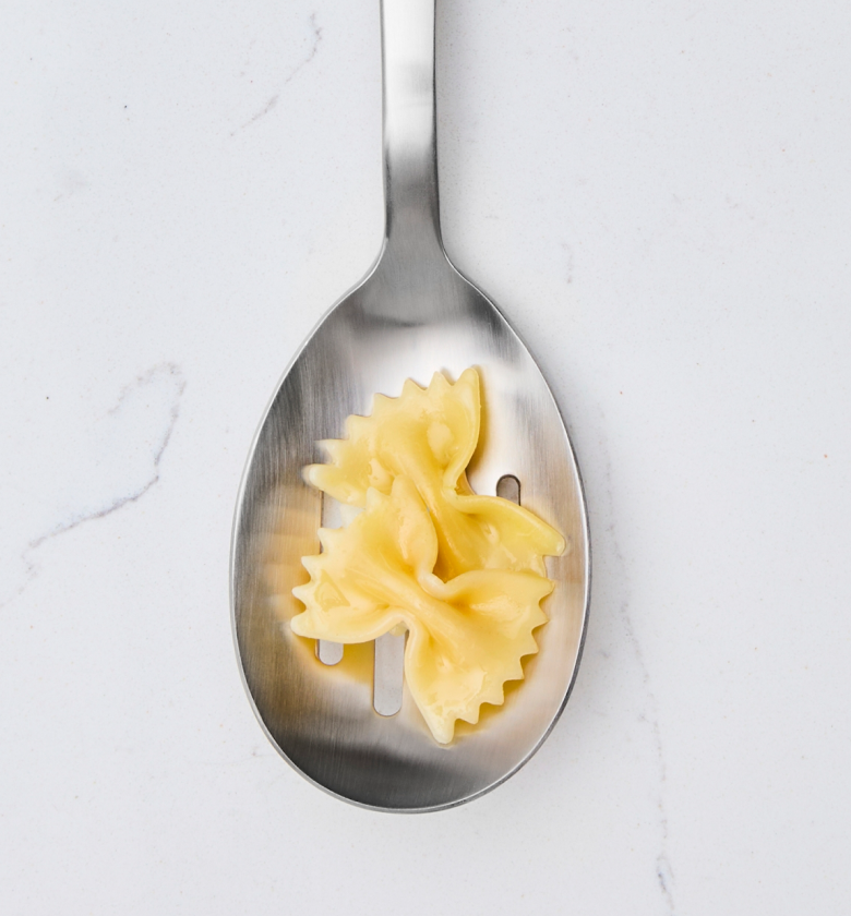 Cooked farfalle bow-tie pasta on a stainless steel slotted spoon